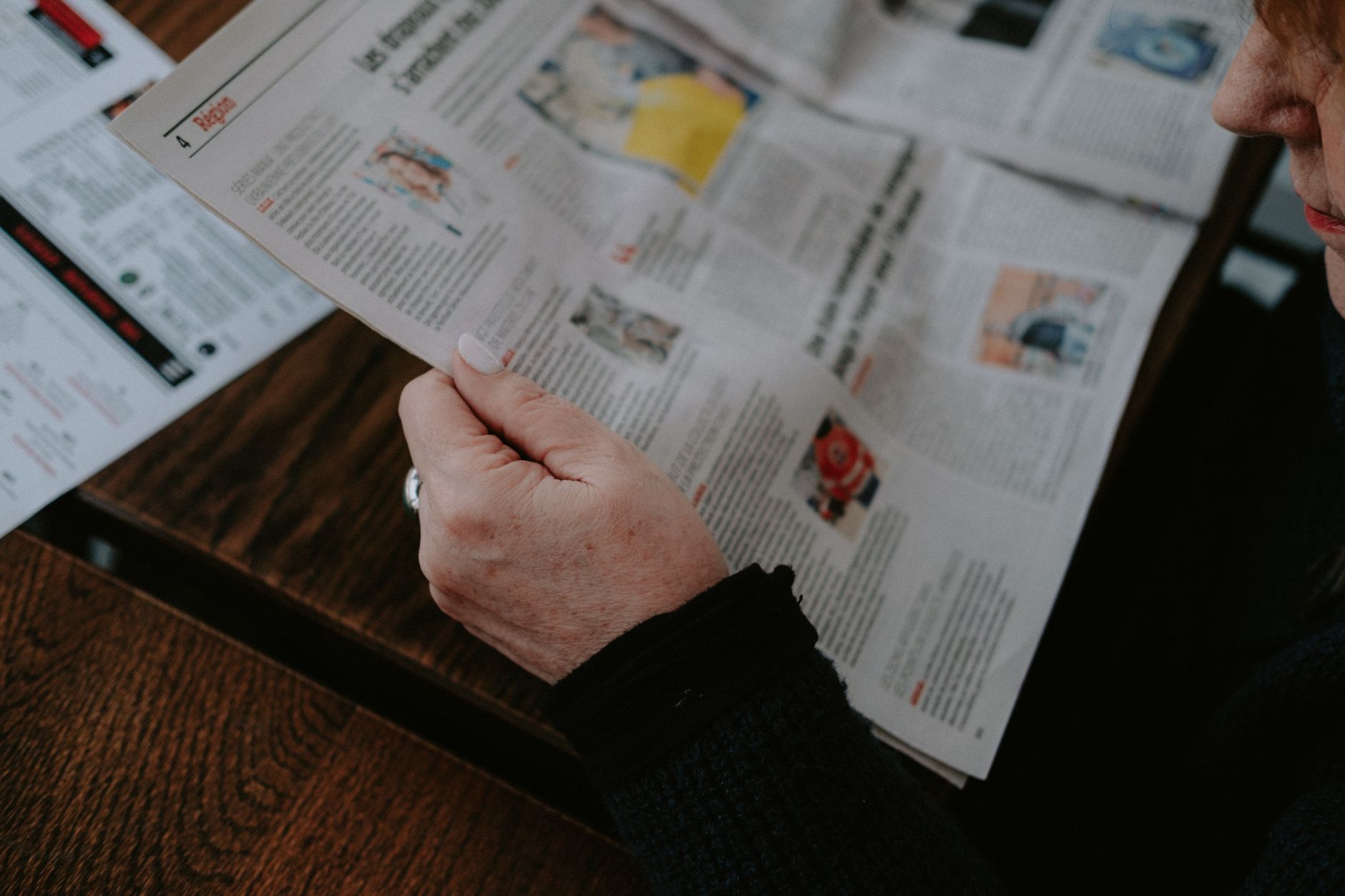 Adult reading a newspaper indoors. Captures focus and interest. — UFABET: Best Odds in Sports Betting